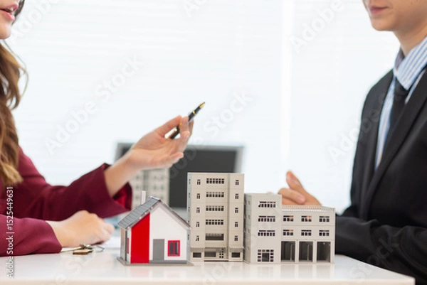 Obraz Inside a real estate office a real estate agent is presenting a condominium unit for sale to a client and offering a valuable promotion to entice the client to purchase their own property. copy space