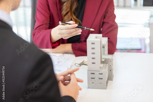 Obraz Inside a real estate office a real estate agent is presenting a condominium unit for sale to a client and offering a valuable promotion to entice the client to purchase their own property. copy space
