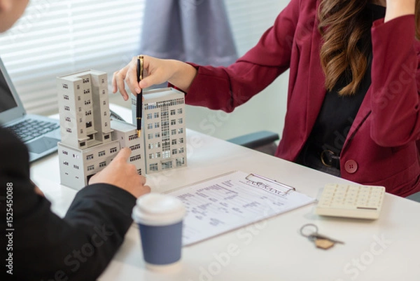 Obraz Inside a real estate office a real estate agent is presenting a condominium unit for sale to a client and offering a valuable promotion to entice the client to purchase their own property. copy space