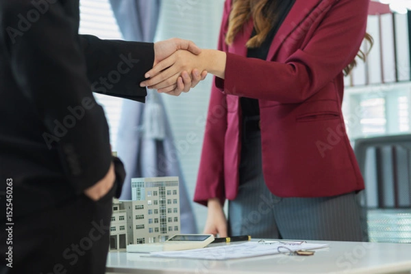 Obraz Inside a real estate office a real estate agent is presenting a condominium unit for sale to a client and offering a valuable promotion to entice the client to purchase their own property. copy space