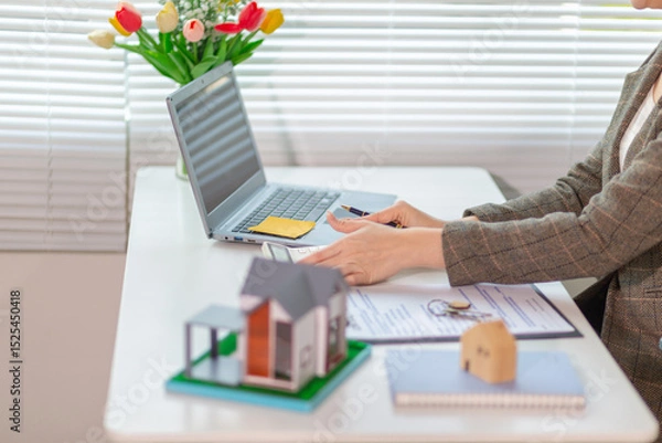 Obraz Inside a real estate office a real estate agent is using a house mockup to present the design and promotions that the client will receive when they sign sales contract. Real estate investment concept