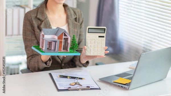 Obraz Inside a real estate office a real estate agent is using a house mockup to present the design and promotions that the client will receive when they sign sales contract. Real estate investment concept