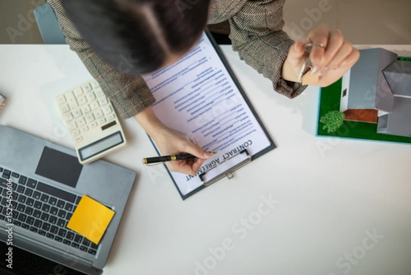 Obraz Real estate agent is in the office with the customer to prepare the documents for the real estate sale. The customer signs the sales contract before handing over the property to the customer.