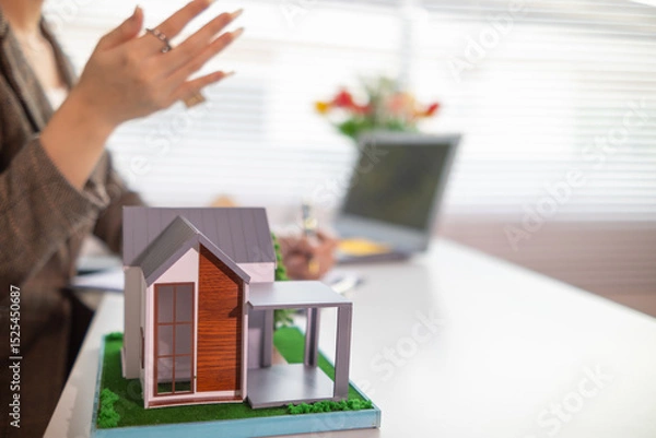 Obraz Inside a real estate office a real estate agent is using a house mockup to present the design and promotions that the client will receive when they sign sales contract. Real estate investment concept