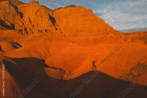 Obraz silhouette and shadow of tourist traveler against red desert mountains at sunset, Bogutty Ridge in spring Kazakhstan