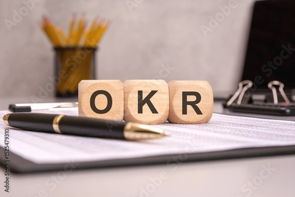 Obraz wooden cubes spelling OKR on a desk with pen and documents