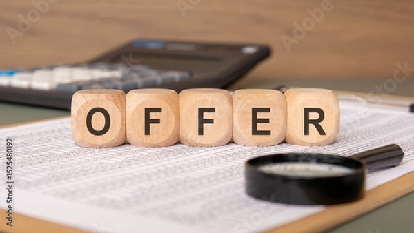 Fototapeta wooden blocks spelling OFFER on financial spreadsheets with calculator and magnifier