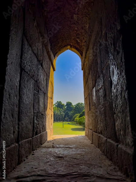 Obraz Stone arch window opening to a peaceful garden. Framed view of green nature, trees, and soft grass,