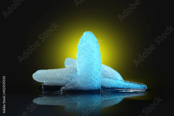 Obraz Ice melting. Pieces of melting ice on a dark background. Colored blue yellow backlight. Selective focus