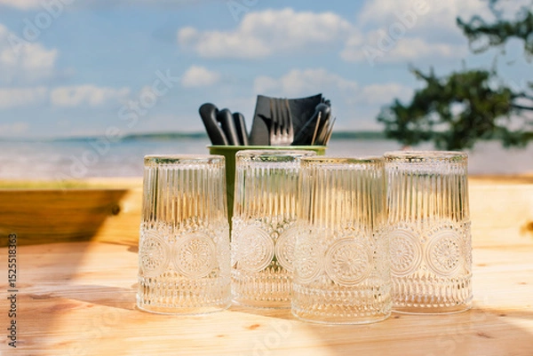 Obraz Table de restaurant ou de camping avec des verres posée sur une table en bois face a la mer