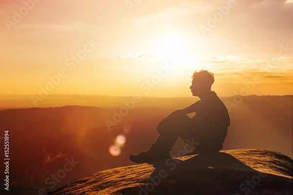 Obraz Silhouette of a man standing and rise his hands up in the air during sunset