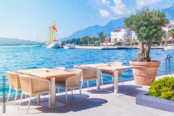 Fototapeta Tivat,Montenegro waterfront dining experience in Boka Bay with stunning Adriatic views and serene ambiance,featuring an inviting outdoor cafe restaurant,clear blue waters,majestic mountains and yachts