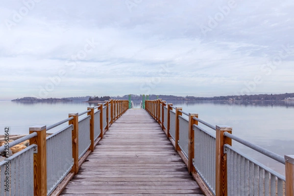 Fototapeta pier leading out to ocean with horizon on cloudy day