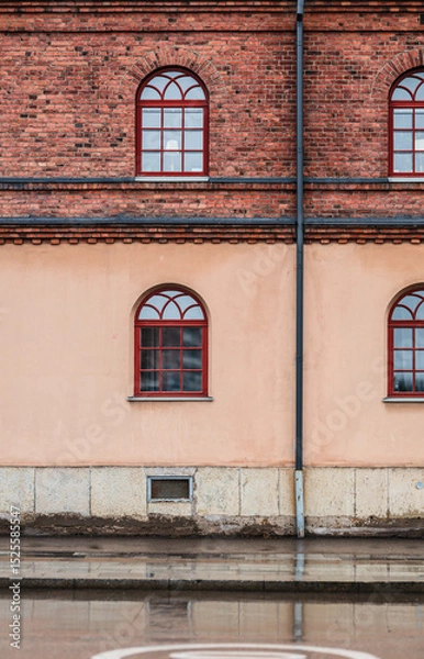 Fototapeta Symmetrical brick and stucco wall with arched windows.