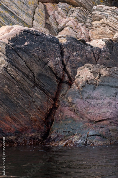 Fototapeta rugged coastal rock formations with dark and weathered surfaces.