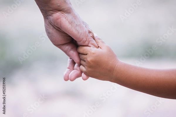 Fototapeta Grandmother and child little girl holding hand together with love in vintage color tone