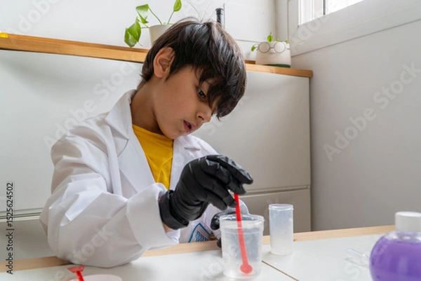 Fototapeta Boy doing science experiment at home with protective gloves