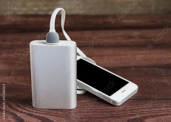 Obraz Charging smartphone with power bank on wooden background