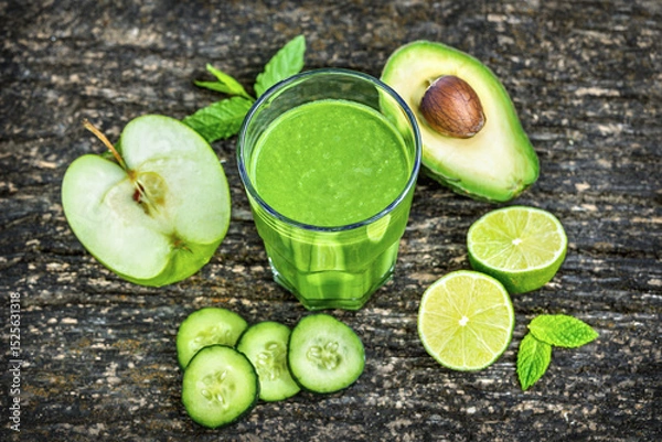 Fototapeta Glass of green detox smoothie with avocado cucumber lime and apple on rustic wooden background, healthy detox drink concept