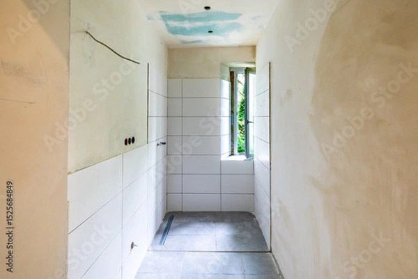 Obraz enovated rbathoom with plaster wall and wooden panels at the floor before covered by woodchip wallpaper after wall plastering