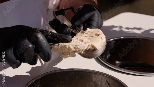 Fototapeta Close up of gloved hands using an ice cream scoop to serve the famous Tartufo dessert in Pizzo, Calabria