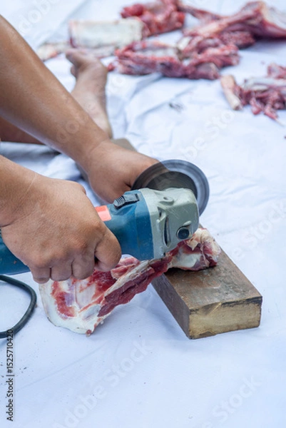 Fototapeta a man is cutting the bones of a cow or sheep with a grinding machine