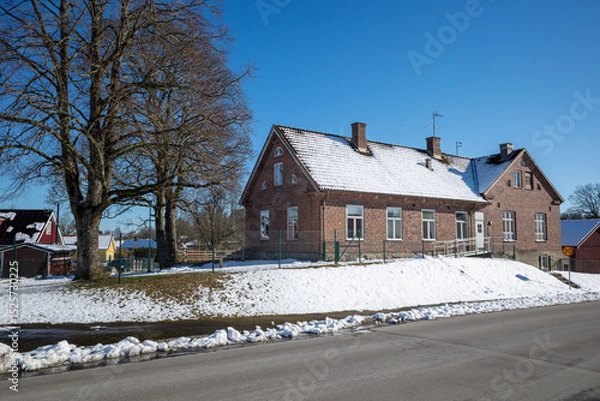 Obraz Old Roinge school building with snow-covered roof and winter landscape in Haessleholm, Sweden