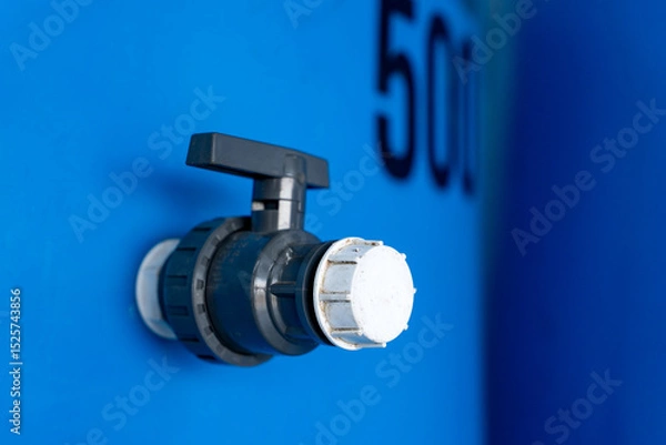 Fototapeta "close-up of a plastic valve attached to a blue water tank, featuring industrial design and functionality. ideal for themes of plumbing, engineering, or water management."