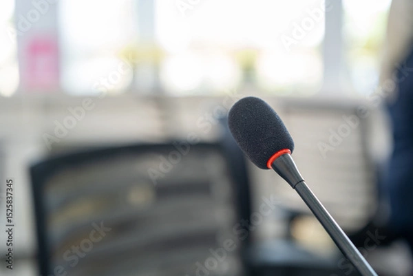 Fototapeta Close-up of a black gooseneck microphone with red accent in a modern office setting, used for communication or public address systems.