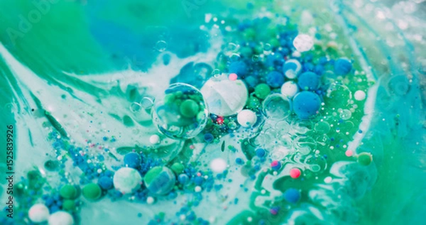 Fototapeta Drop emulsion. Oil paint bubble. Colorful acrylic ball flow in green liquid. Art wave fizz blue particles mix abstract defocused background.