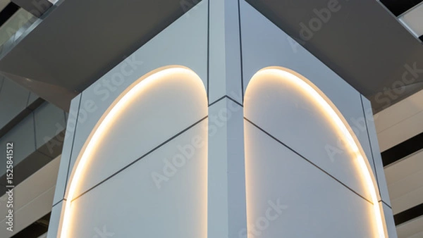 Fototapeta Modern architectural corner with curved LED lighting on smooth gray panels, captured from low angle in a contemporary indoor space.