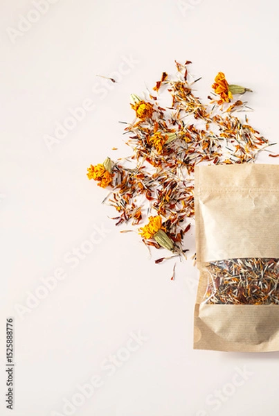 Fototapeta Dried Marigold Petals and Whole Flowers Scattered Next To an Open Craft Paper Bag, Top View with Copy Space.
