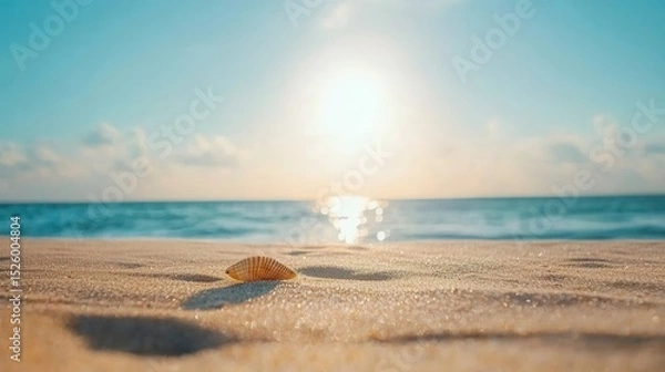 Fototapeta summer concept. Serene beach scene with a shell and glowing sun over the ocean.