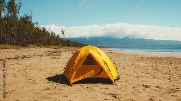 Fototapeta summer concept. A bright yellow tent on a sandy beach with mountains in the background.