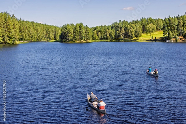 Obraz People paddling canoes on a lake in a forest on a sunny summer day