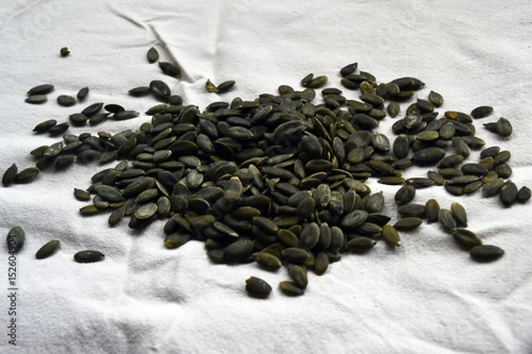 Fototapeta Peeled pumpkin seeds on a white tablecloth
