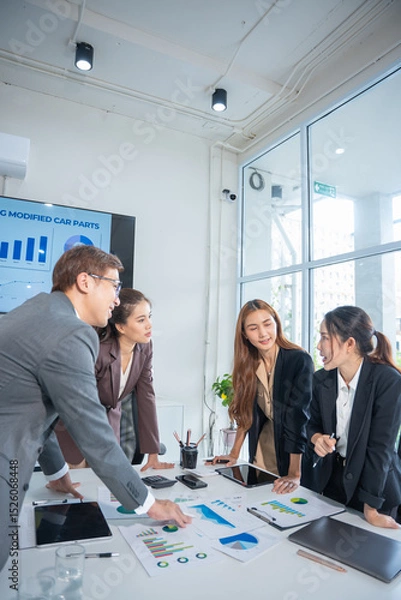 Obraz Group of confident professional business people pointing at graphs and charts to analyze marketing data to plan new sales strategies to increase productivity in modern office.