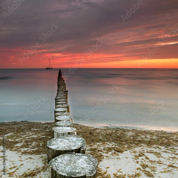 Fototapeta Timeless Shores: Weathered Wooden Groynes Under a Vibrant Sunset