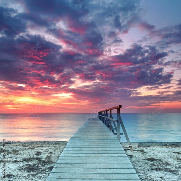 Fototapeta a Lonely weathered wooden pier Overlooking a Colorful Sunset by the Sea