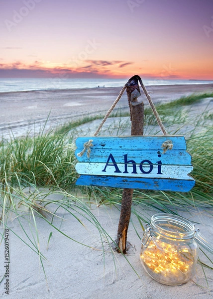 Fototapeta weathered sign with AHOI text in the dunes in sunset sky