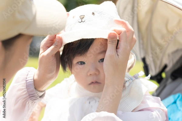 Obraz お母さんに帽子をかぶせてもらっている赤ちゃん