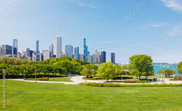 Fototapeta Sunny view of downtown Chicago with iconic skyscrapers rising above a lush green park meadow
