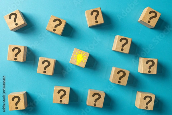 Obraz A single wooden block with a yellow lightbulb idea icon surrounded by blocks with question marks. Concept for finding a solution, problem-solving, answering questions, and creative thinking.