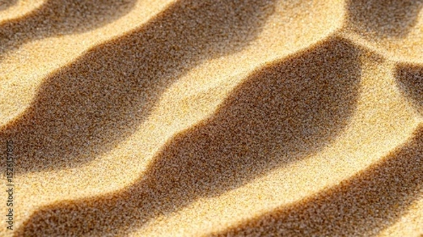 Fototapeta A close-up of a sand dune with ripples in the sand, illuminated by sunlight, with a shadow cast by a nearby object.