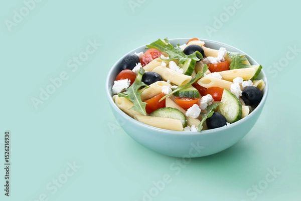 Fototapeta Mediterranean Pasta Salad in bowl with Fresh Vegetables and Herbs on green background. Copy space