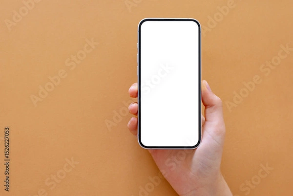 Fototapeta Phone with empty screen in hand, mockup on neutral beige background