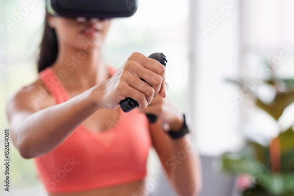 Fototapeta Asian woman wear virtual reality glasses and train boxing with joystick control at home
