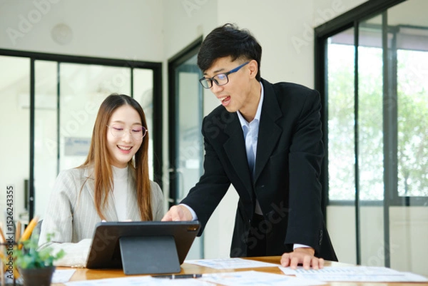 Obraz Two business people discuss financial strategy and collaborate with colleagues.