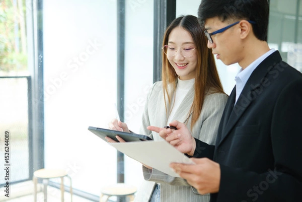 Obraz Two business people discuss financial strategy and collaborate with colleagues.
