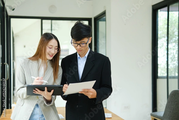 Obraz Two business people discuss financial strategy and collaborate with colleagues.